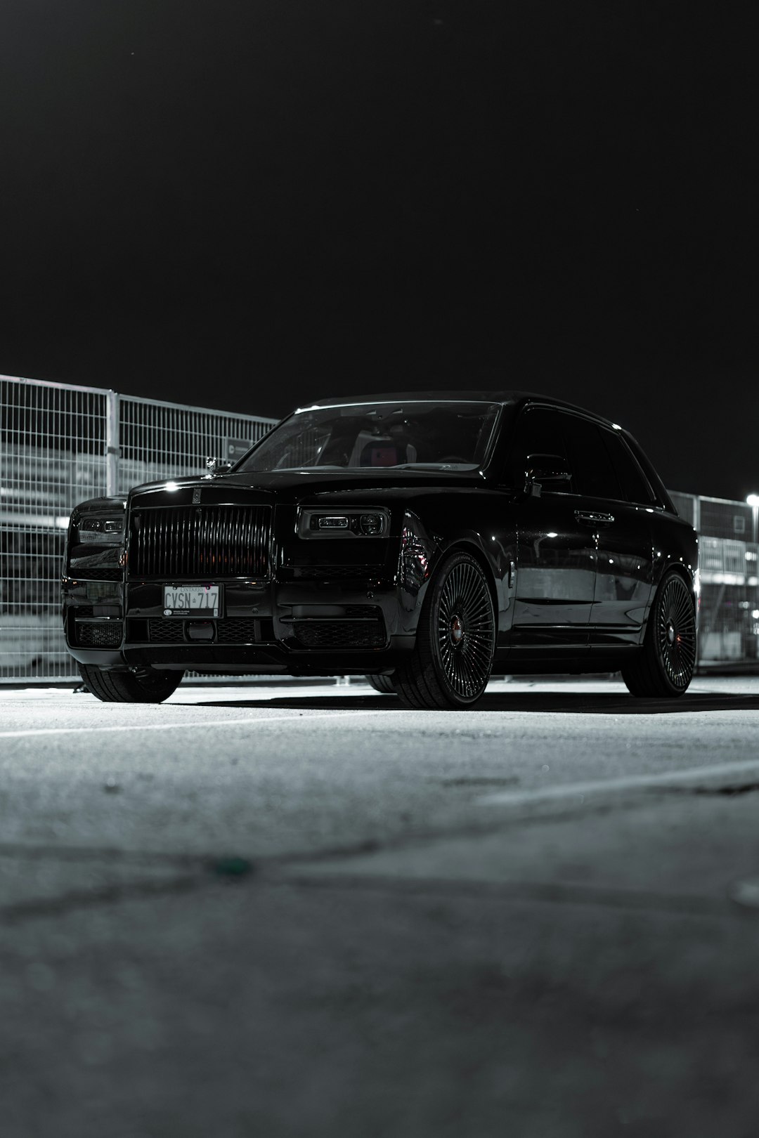a-black-car-parked-in-a-parking-lot-at-night-dxmh2afl9o8