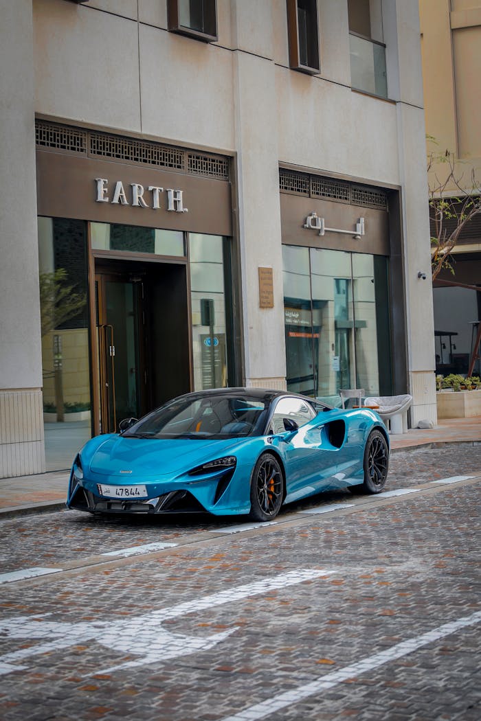 A sleek blue sports car parked in front of an urban building with stylish architecture.